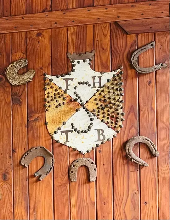 Okrasni grb na steni in podkve, tradicionalen detajl v notranjosti koče