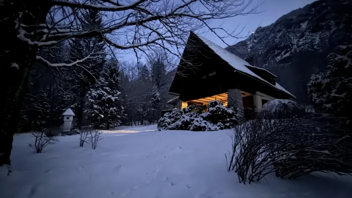Snežak na vrtu Koče pri Rdeči Bukvi, koča razsvetljena v somraku